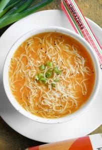 Soup in a bowl topped with chives and crushed black pepper