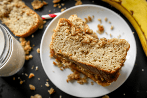 A few pieces of keto banana bread stacked on top of one another on a white plate.