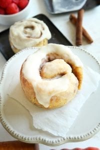 A keto cinnamon roll on a piece of parchment paper on a white saucer