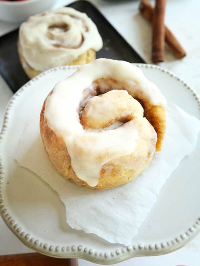 A keto cinnamon roll on a piece of parchment paper on a white saucer