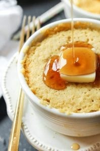 A pancake made in a ramekin, that's topped with butter, and syrup is being poured on it.