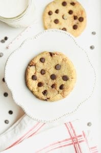 A chocolate chip cookie sitting on a raised plate.