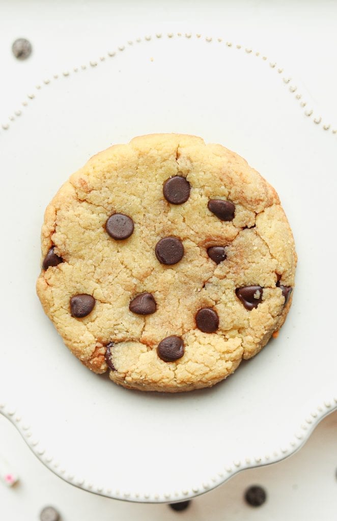 A chocolate chip cookie laying on a plate.