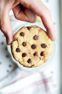 A chocolate chip cookie being held between 2 fingers.