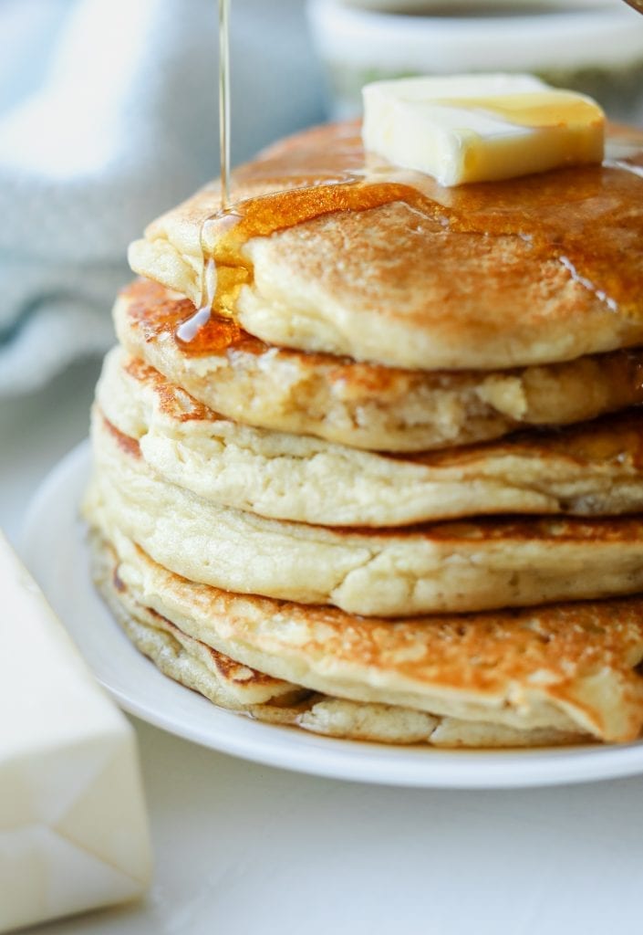 A stack of pancakes with syrup running down the left side of them.