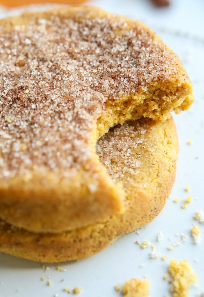 2 pumpkin spice cookies stacked on top of one another, and the top cookie has a bite taken out of it.