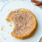 A keto pumpkin spice cookie with a bite taken out of it sitting on a serving plate.