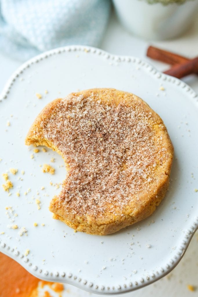 A keto pumpkin spice cookie with a bite taken out of it sitting on a serving plate.