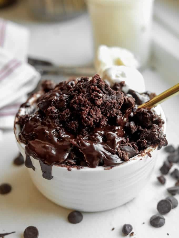 A Chocolate Lava Mug Cake sitting on a table with a fork inside of it.