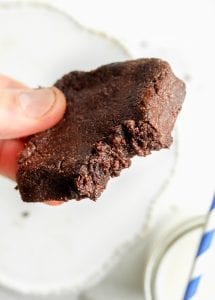 A brownie with a bite taken out of it being held in a hand.