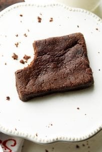 A brownie sitting with a bite taken out of it.