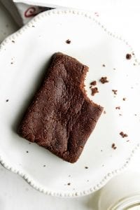 A brownie with a bite taken out of it sitting on a plate.