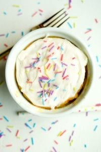 A birthday cake mug cake topped with frosting and sprinkles.