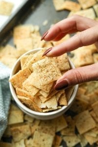 Someone holding a lemon dill keto cracker in their fingers.