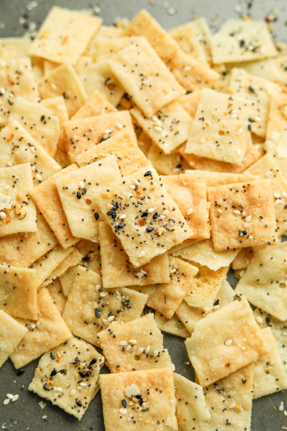 Keto cheese crackers laying on a tray covered in everything bagel seasoning.