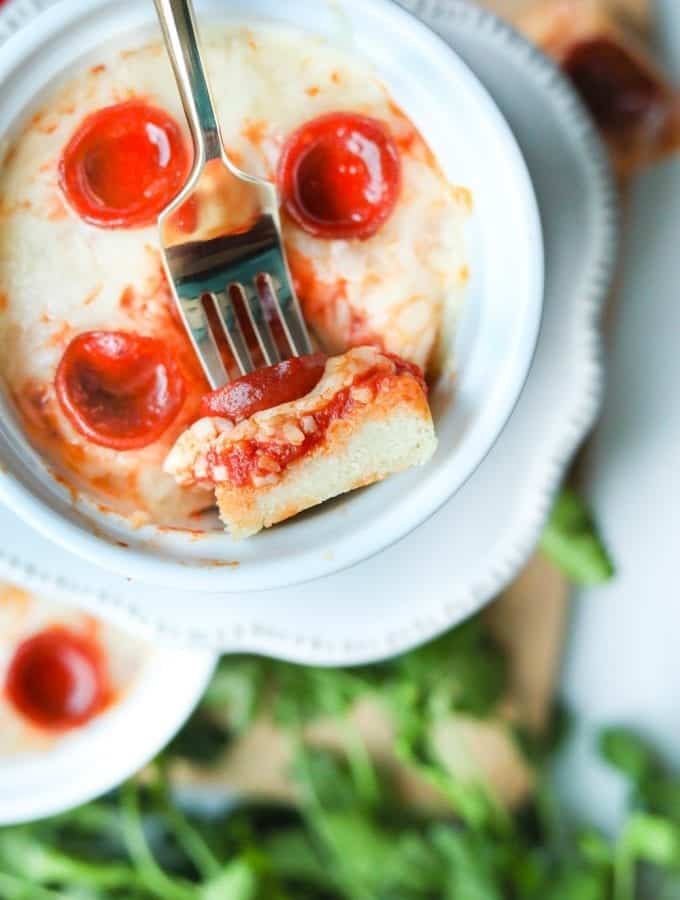 Pizza laying in a dish with a fork holding a piece