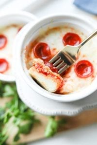 Pizza in a dish with a piece stuck to a fork.