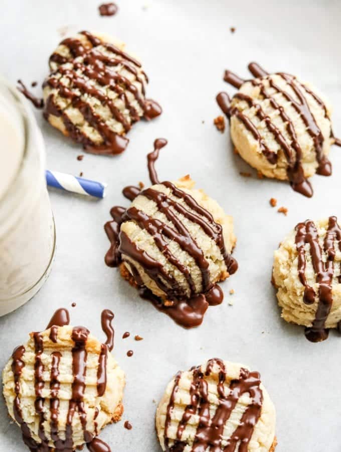 6 butter cookies laying next to a glass of milk.