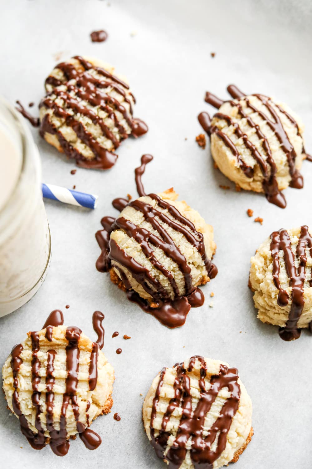 6 butter cookies laying next to a glass of milk.