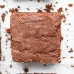 Keto brownies cut into square laying on parchment paper.