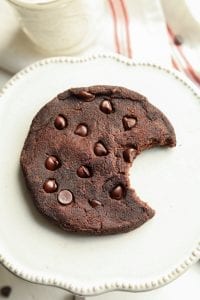 A chocolate keto cookie with a bite take out of it.