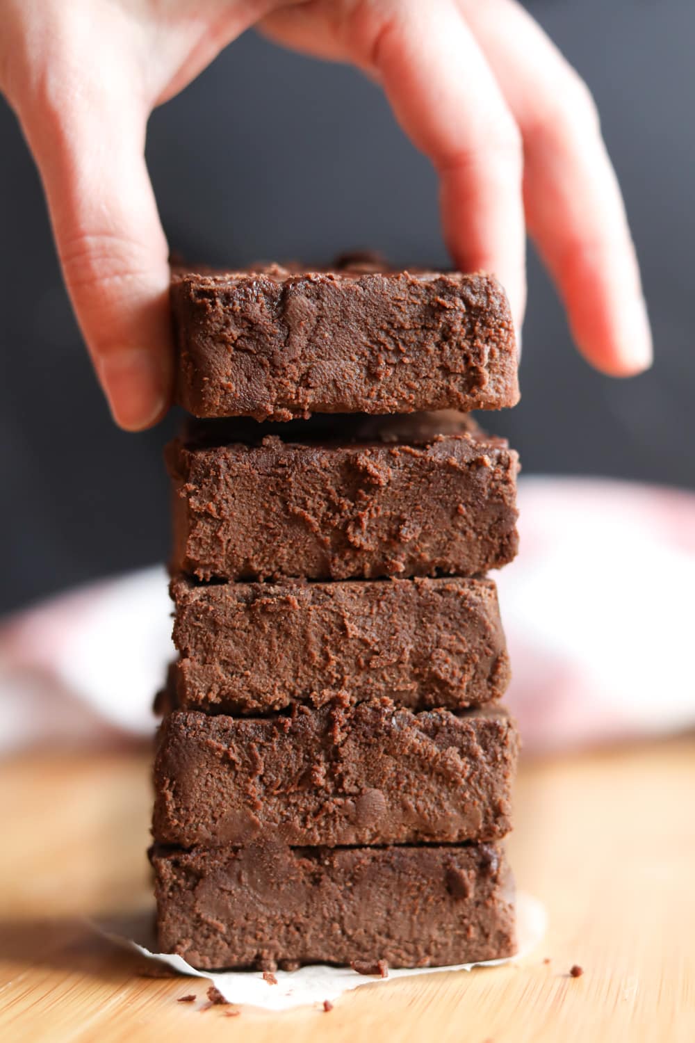 A stack of brownies with a hand taking the top one.