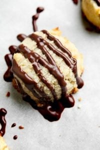 A butter cookie laying on a baking tray drizzled with chocolate.