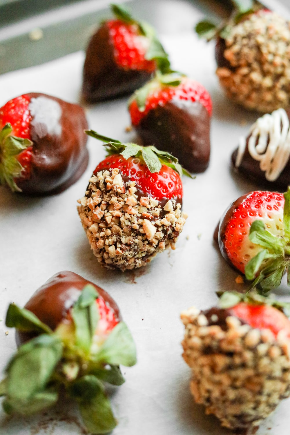 Low carb keto Chocolate covered strawberries dipped and peanuts and other things laying on a tray.