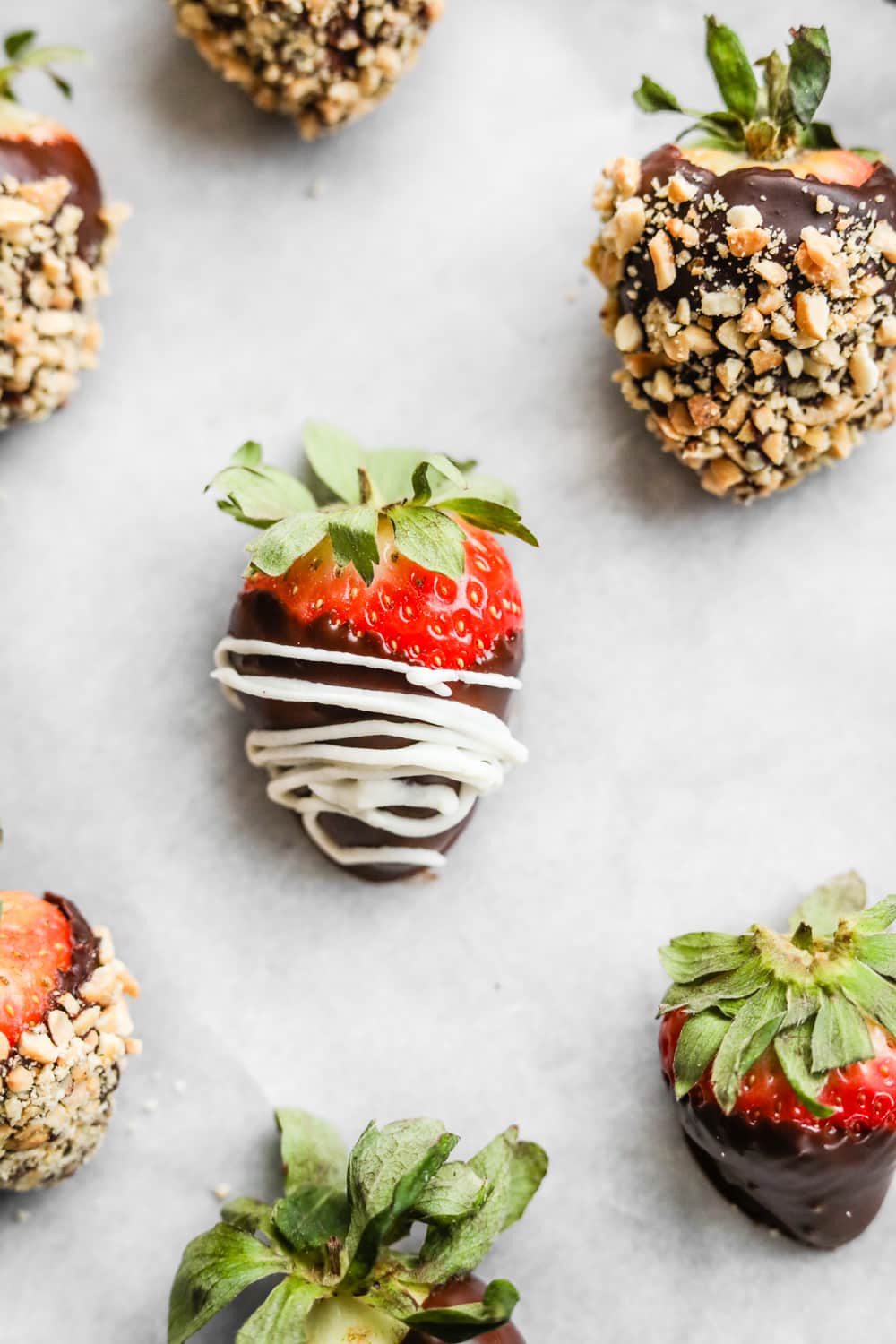 Chocolate covered strawberries on white parchment paper.