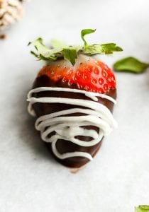 A keto chocolate covered strawberry with a cream drizzle