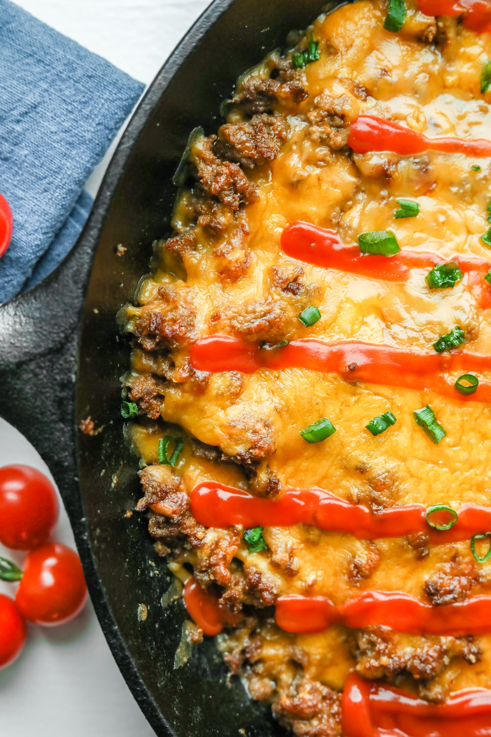 Half of a keto cheeseburger casserole covered in chives and low carb ketchup.