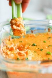 Low carb chicken wing dip being scooped up with a stick of celery.