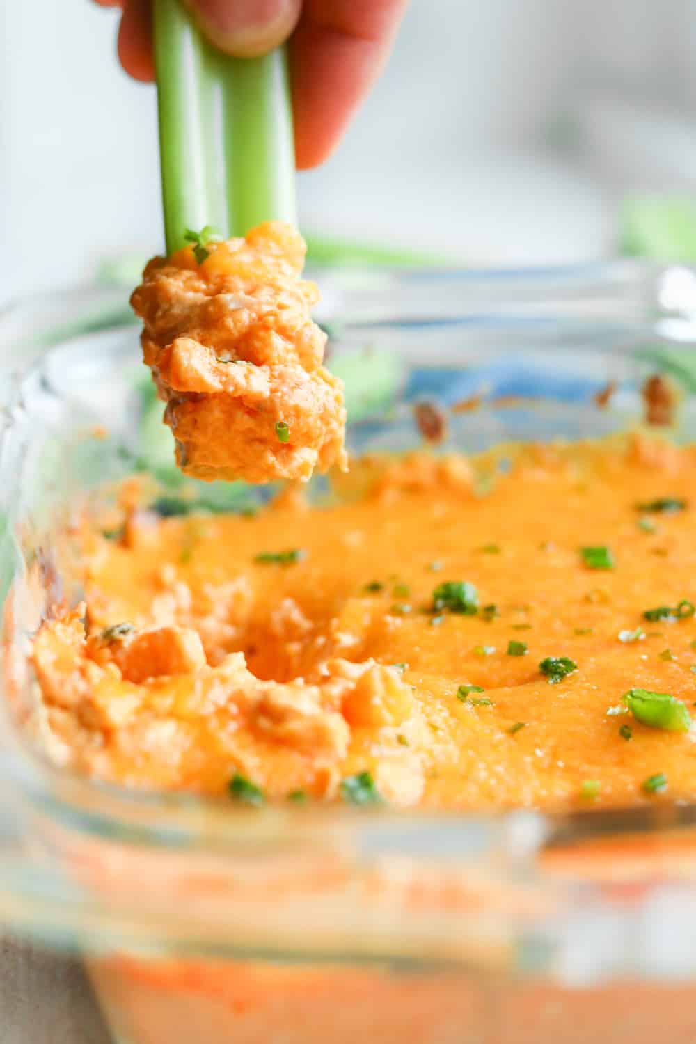 Low carb chicken wing dip being scooped up with a stick of celery.