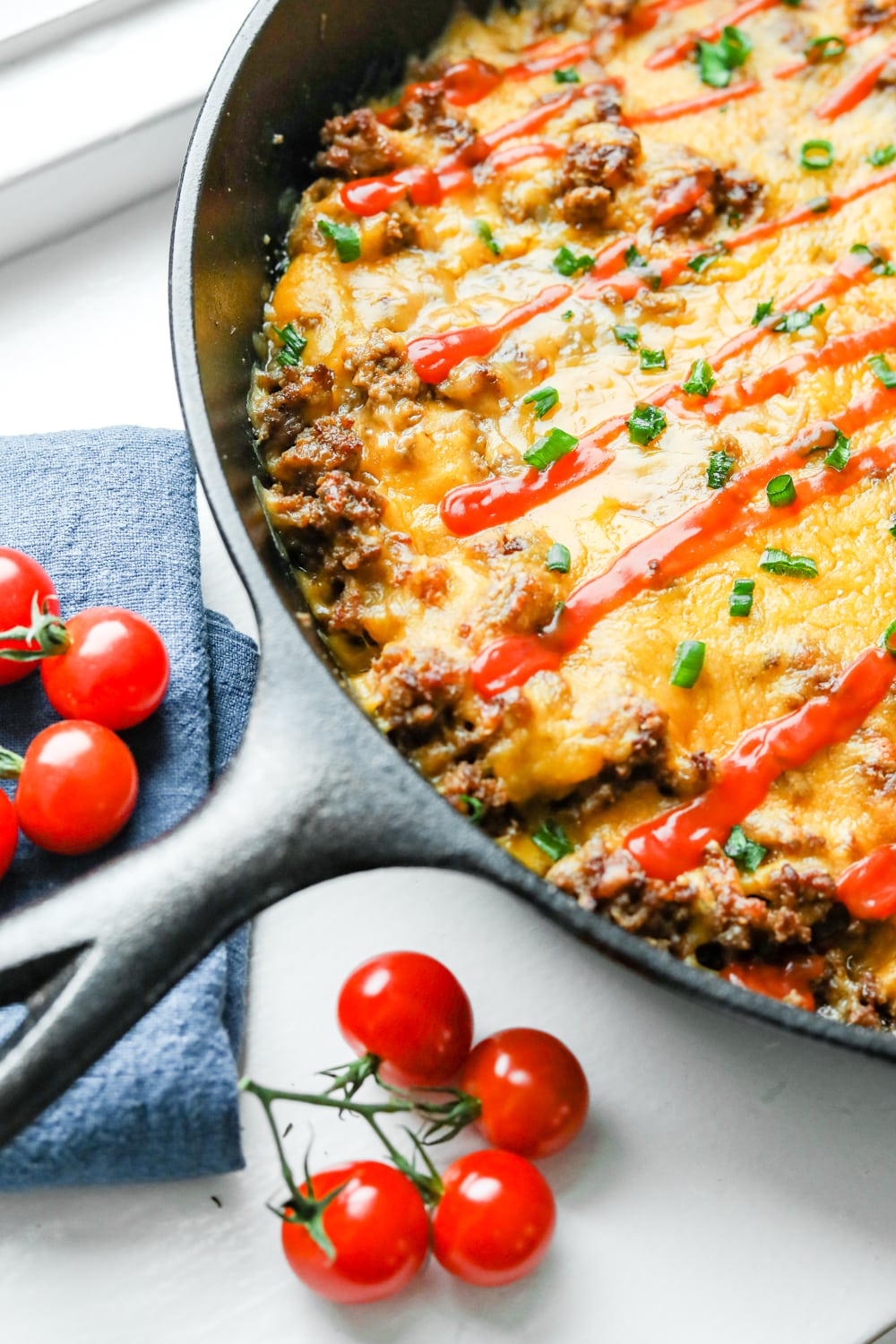 A cheeseburger casserole topped with chives and low carb ketchup