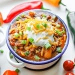 A bowl of keto chili surrounded by tomatoes and peppers.