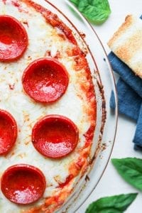 Low carb pizza dip next to a blue napkin, low carb bread, and basil