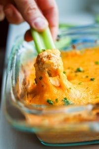 Low carb buffalo chicken wing dip being pulled out of a tray with celery.