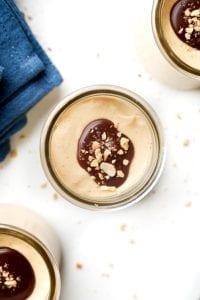 A jar of peanut butter keto mousse sitting on a table next to a napkin.