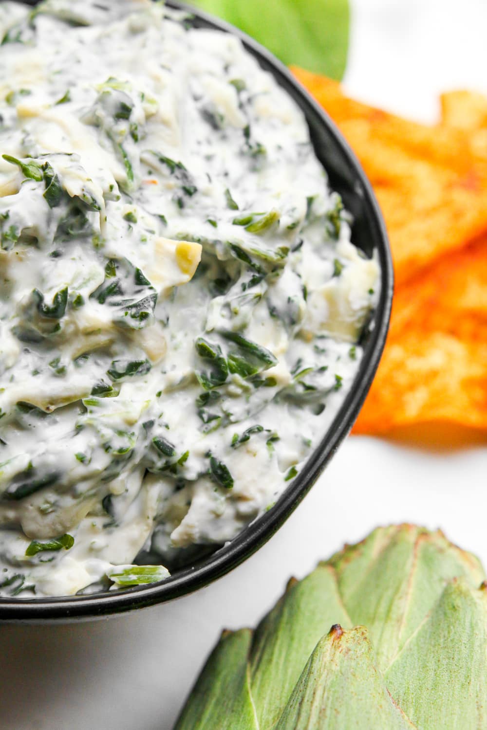 An up close view of low carb spinach and artichoke dip in a bowl.