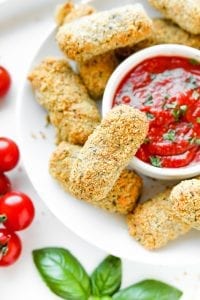 A plate of low carb mozzarella sticks next to marinara sauce.