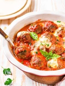 Keto meatballs in a tomato sauce topped with cheese and basil.