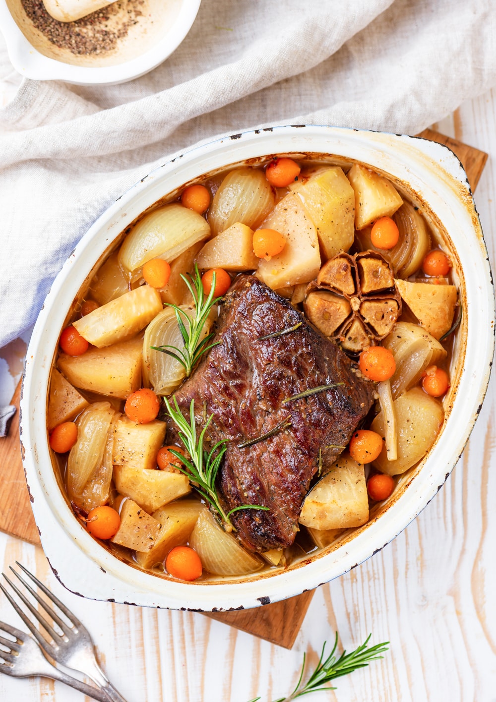 A pot roast surrounded by vegetables in a dutch oven.