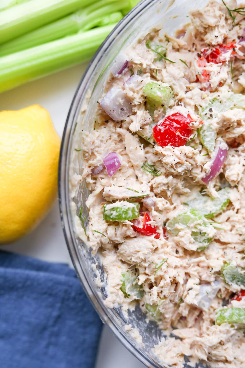 A bowl of low carb tuna salad surrounded by a lemon and celery.