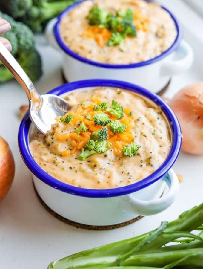 A spoon going into a bowl of keto broccoli cheese soup.