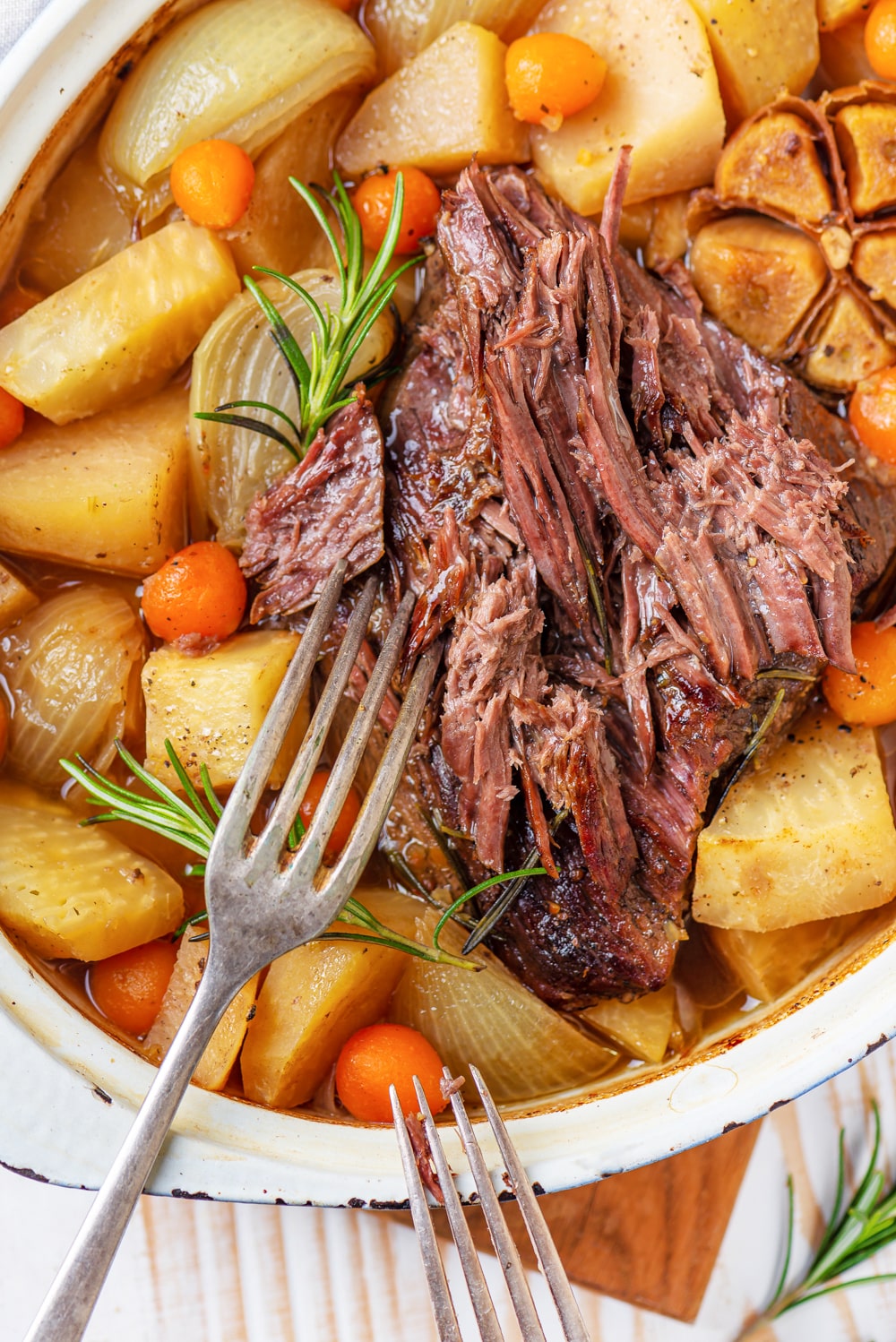 A pot roast just starting to be shredded by a fork.
