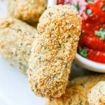 A keto mozzarella stick next to a cup of marinara sauce.