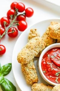 A plate of mozzarella sticks next to a bowl of low carb marinara sauce.