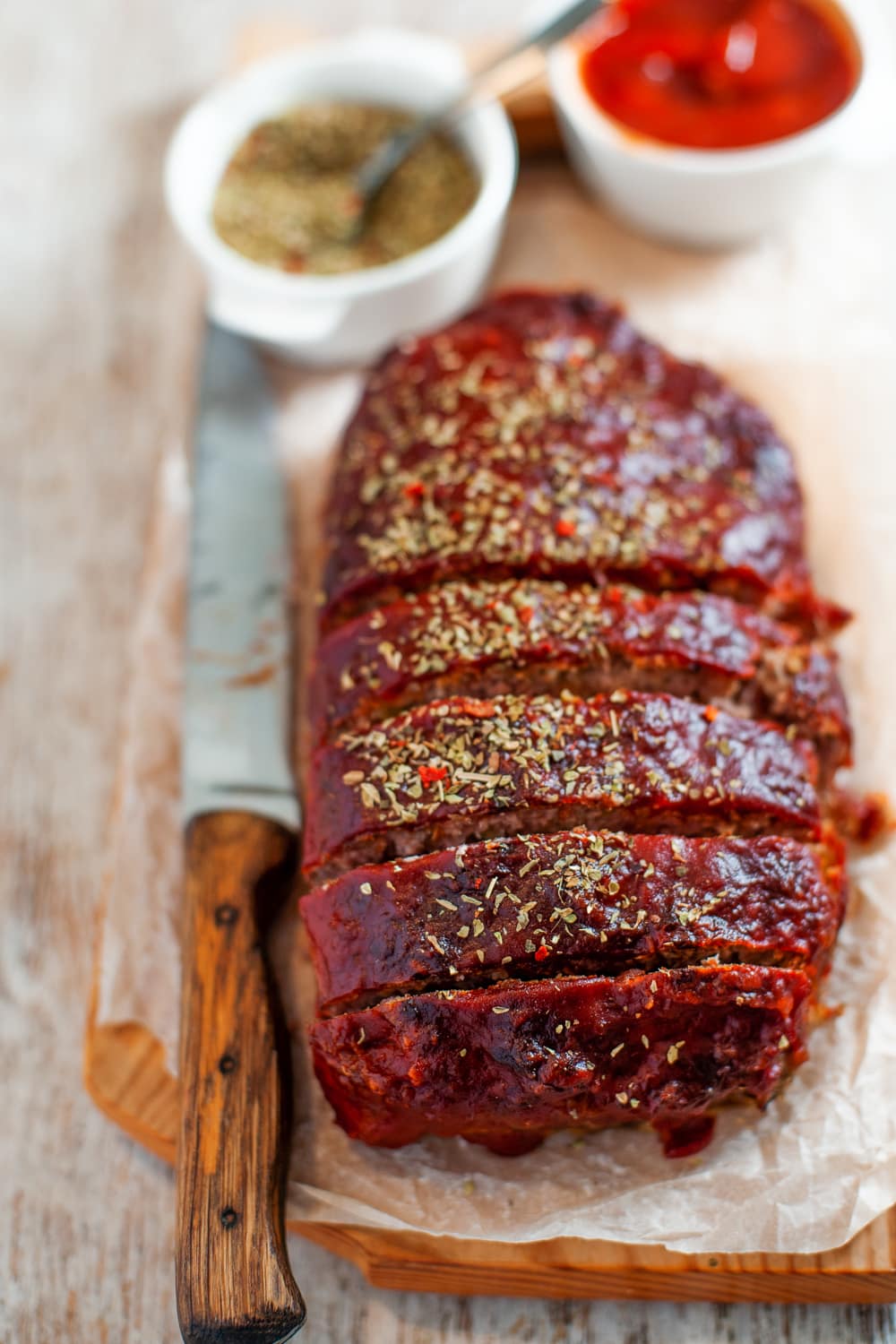 An entire meatloaf cut into slices with a knife next to it.