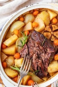 A keto pot roast with a fork next to it surrounded by low carb vegetables.