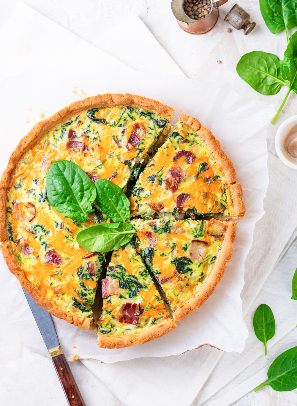 A keto quiche sliced into 3 pieces with a knife next to it.